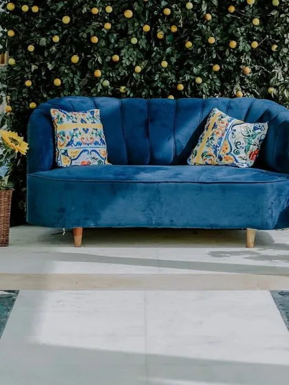A pop of contrast. This plush blue sofa provides a striking focal point and comfortable seating, set against a photo wall made of fresh greenery and bright yellow lemons.