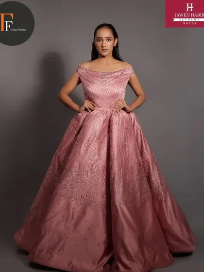 A model in an elegant pink ball gown, with makeup and hair done by our students for a professional photoshoot.
