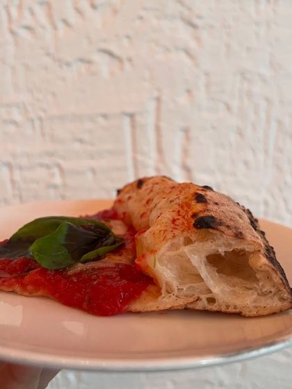 Just a single slice of our Margherita, showcasing the perfect crust. It's sturdy enough to hold but light enough to fold.