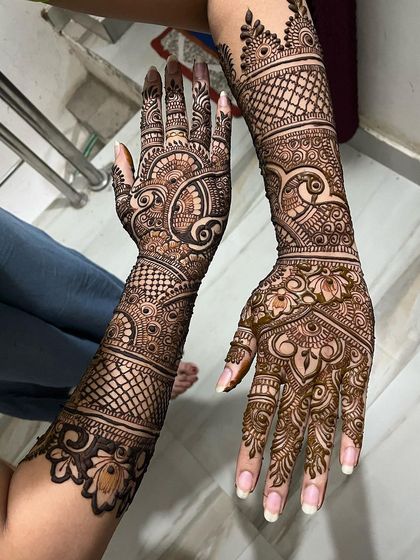 A dynamic and flowing bridal design. The patterns swirl gracefully up the arm, connecting the detailed work on the hand with the bands on the forearm.