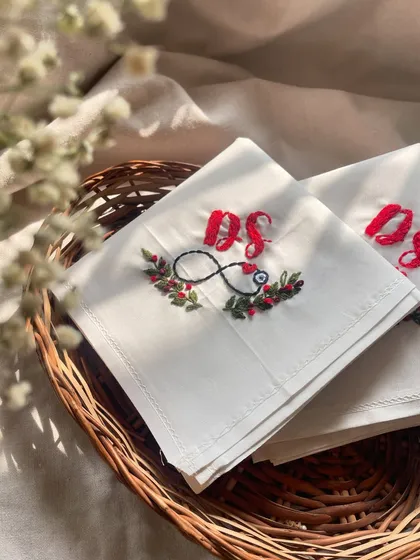 A set of custom handkerchiefs, beautifully embroidered with couple's initials, an infinity symbol, and a nazar bead for protection.