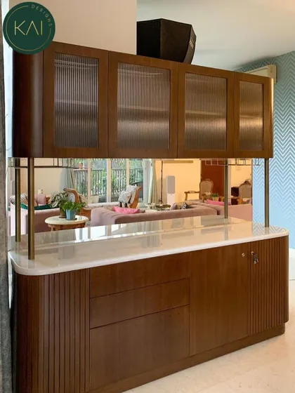 This custom-designed bar and crockery unit showcases our expertise in creating functional art. The rich wood finish, curved corners, and fluted glass doors provide a sophisticated storage solution that seamlessly divides and enhances the living space.