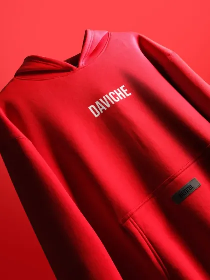 This vibrant red hoodie for the brand DAVICHE is captured with bold, directional lighting to emphasize the fabric's quality and the clean logo design. This style of apparel photography is perfect for brand lookbooks and hero website images.