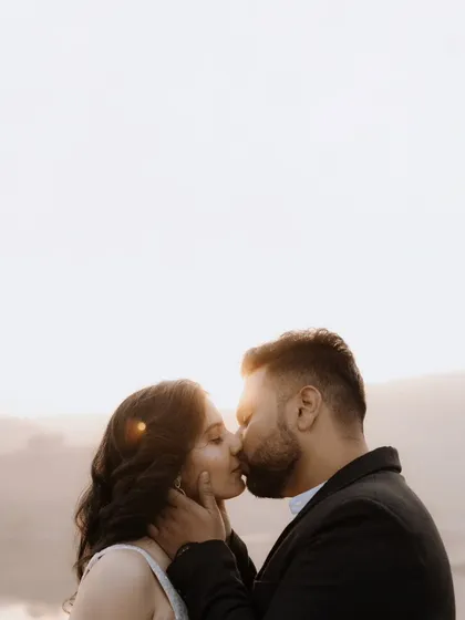 An intimate and passionate kiss, backlit by the bright, hazy sky. This close-up shot is all about raw emotion and connection.