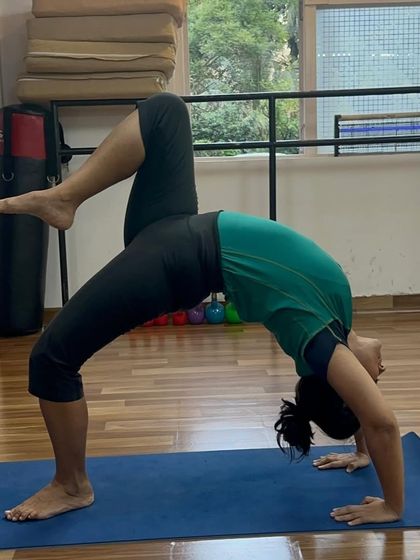 Eka Pada Urdhva Dhanurasana (One-Legged Wheel Pose) is a challenging posture that requires immense strength and balance. This student demonstrates beautiful form.