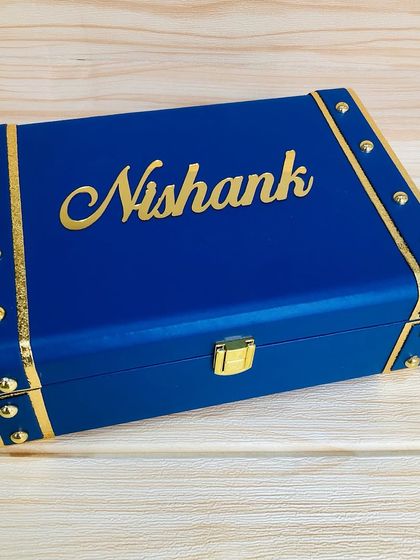 The outside of a personalized travel accessories trunk. I added the name "Nishank" in a beautiful gold script to make the keepsake box as special as the gifts inside.