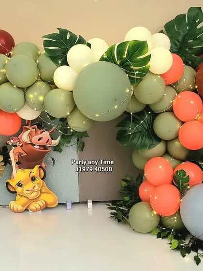 A jungle or Lion King theme decoration, perfect for a cake smash photoshoot or first birthday. This setup uses green, orange, and brown balloons with artificial leaves and a Simba cutout.