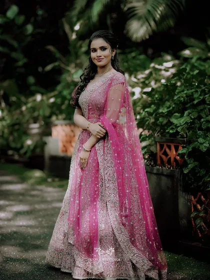 A full-length portrait of the bride-to-be, her sparkling pink lehenga shining in the light.