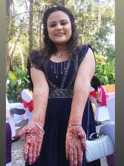 A happy client posing with her beautiful guest mehendi at an outdoor event. The dark stain looks stunning against her blue dress.
