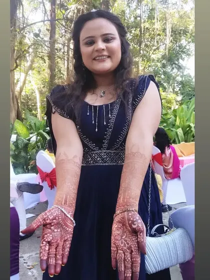 A happy client posing with her beautiful guest mehendi at an outdoor event. The dark stain looks stunning against her blue dress.