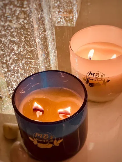 Here you can see two of my candles burning brightly. The one in the blue jar has my signature crackling wooden wicks, while the other has a traditional cotton wick, showing the different options I offer.