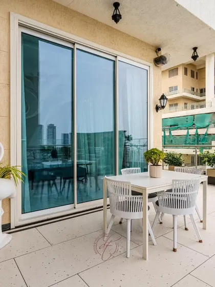 This spacious terrace features a chic outdoor dining set and whimsical flamingo-shaped planters, adding a playful touch to the elegant design. The large sliding glass doors seamlessly connect the indoor and outdoor spaces.