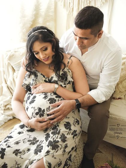 A quiet moment between the parents-to-be. The soft, high-key lighting and neutral tones of the set design create a peaceful and intimate portrait.