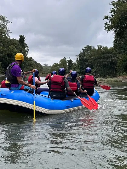 A view from behind shows a rafting team paddling in sync under the guidance of an instructor during a course in Coorg. This demonstrates the learning and teamwork aspect of our programs.