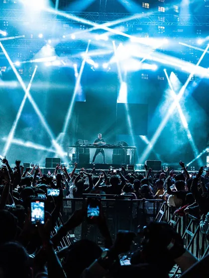 A stunning shot of the stage bathed in blue light, with the crowd reaching for the DJ.