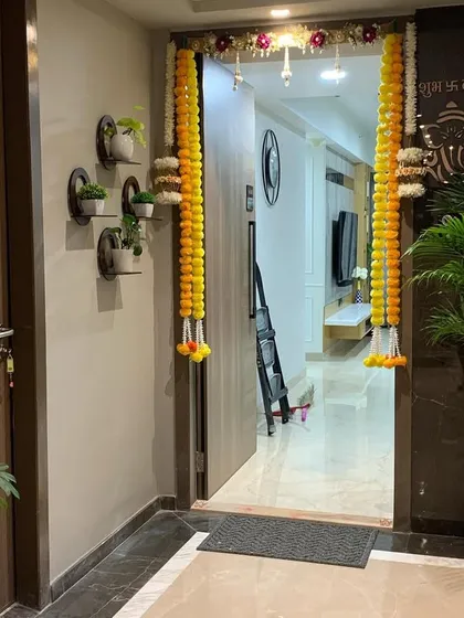 For this home entrance, I created a welcoming green display. A large Areca palm adds height and drama, while a collection of small plants on wall-mounted shelves provides a modern, space-saving decorative element.