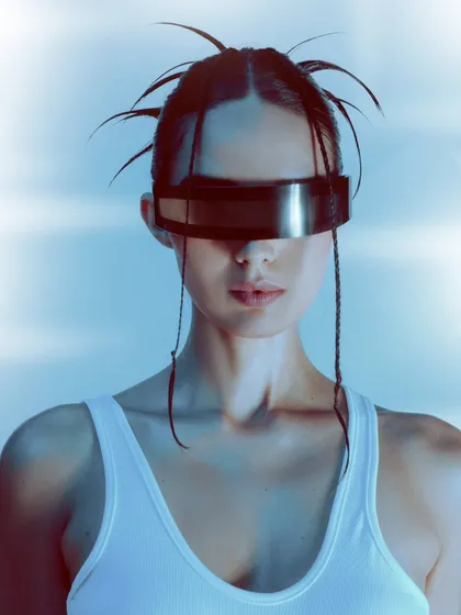 A futuristic beauty editorial using cool, blue-toned lighting and metallic accessories. This close-up on the visor and spiky hair creates a sleek, sci-fi aesthetic.