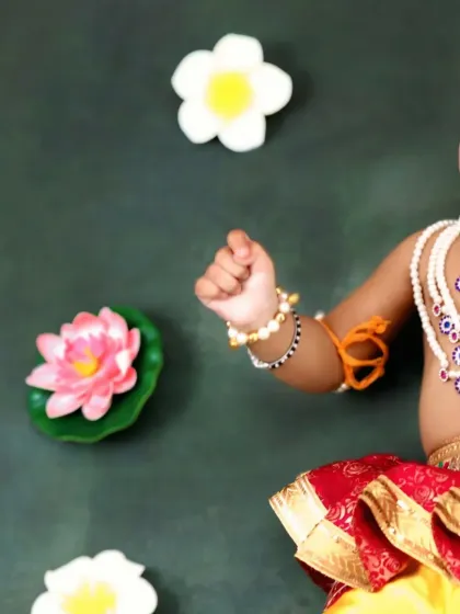 A close-up shot capturing the mischievous smile and sparkling eyes of a baby dressed as Krishna.
