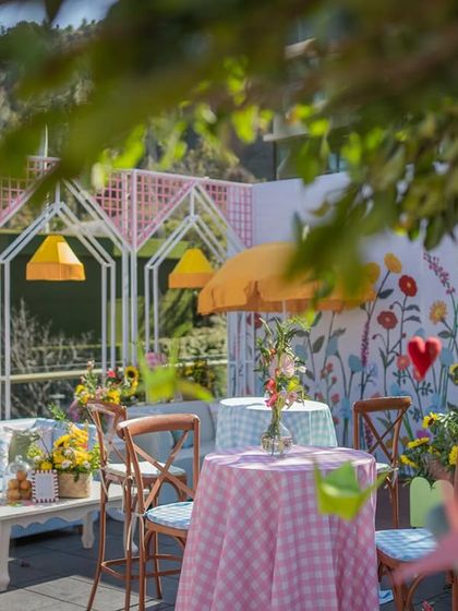 A fun and colorful seating area at the mountain picnic mehendi, with a hand-painted floral wall and checkered tablecloths.