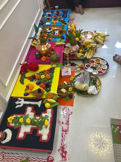 The vibrant and detailed setup for a housewarming puja. The geometric patterns made from rice and pulses are traditional elements that invite prosperity and good fortune into the home.