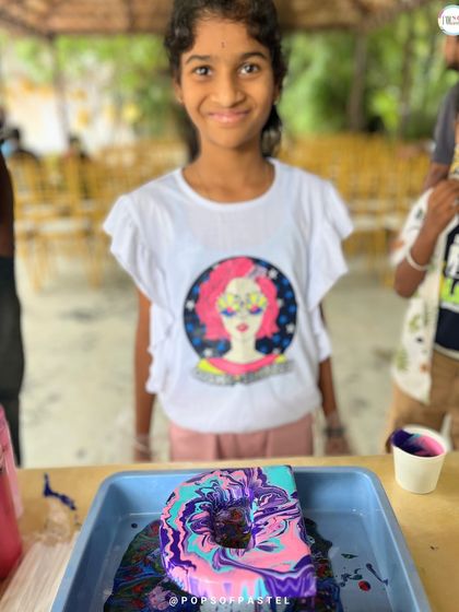 This young participant is all smiles with her colorful, freshly poured initial 'D'. Fluid art is a fantastic activity for kids' parties.
