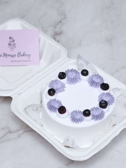 A classic blueberry bento cake. This small cake is perfect for an intimate celebration, topped with fresh blueberries and delicate purple frosting swirls.