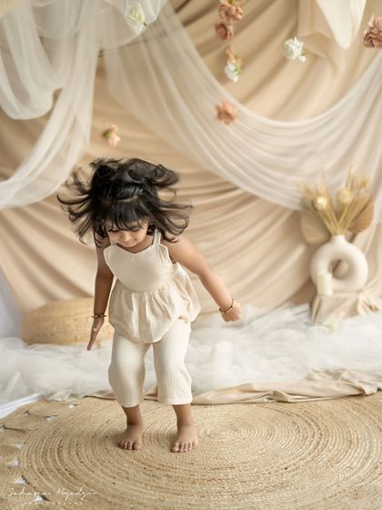 A little girl jumping for joy in a beautiful, draped studio setup. A perfect shot for a milestone session.
