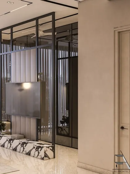 A glass and metal partition with a built-in TV console elegantly divides the sleeping area from a small seating nook or dressing space. The marble base adds a luxurious touch.
