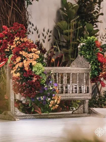 The traditional 'thottil' or cradle, beautifully adorned with flowers, sits at the heart of the indoor orchard. This is where the baby's naming ceremony takes place, surrounded by symbols of life and abundance.