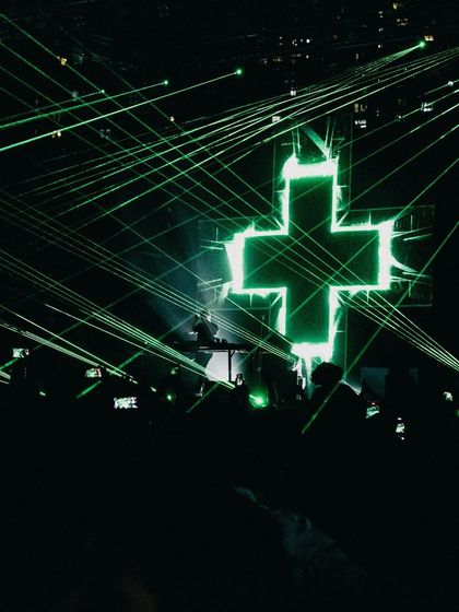 The iconic Martin Garrix cross logo lit up in green lasers, a signature part of his visual show.