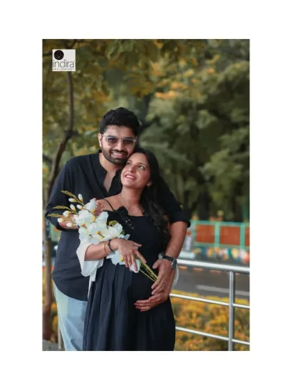 The expecting mother looks up lovingly at her partner while holding a bouquet of white flowers, creating a romantic and dreamy portrait.