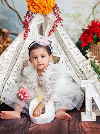 Holding onto the 'O' in 'ONE'. It’s a sweet pose that highlights both the baby and the milestone she is celebrating.