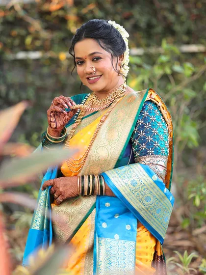 The beauty of a traditional Nauvari saree in vibrant yellow and blue. I created a classic Marathi bridal look for her, complete with a floral bun and glowing makeup.