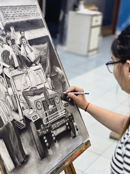 The artist adds details to the front of the jeep in her charcoal drawing, using precise strokes to create a sense of realism and texture.