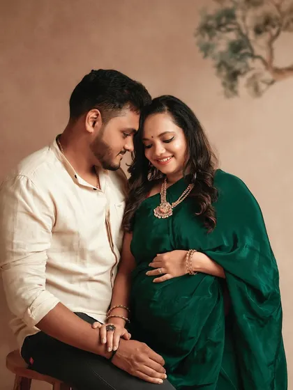 A gorgeous couple captured in a moment of quiet connection. Her emerald green saree adds a touch of royalty to this traditional maternity portrait.
