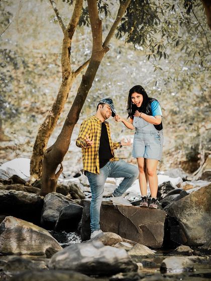 A duplicate of a fun and adventurous shot of a couple by a rocky stream.