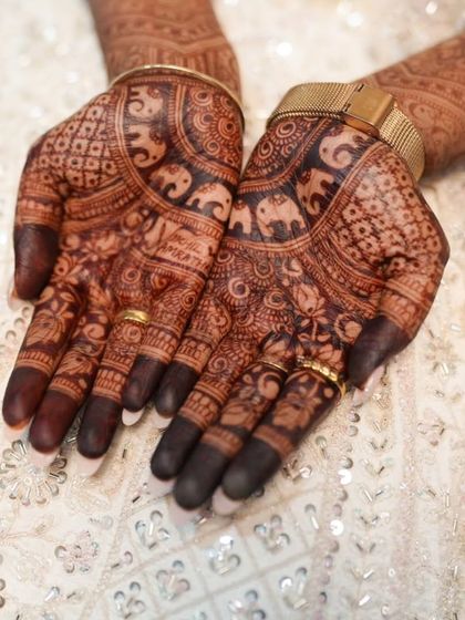 The palms of the bride, showing the rich stain and the personalized names hidden within the design.