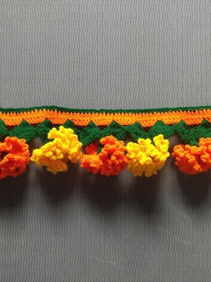 A beautiful toran made with a mix of orange and yellow marigold flowers, perfect for any festive occasion.