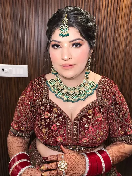 A close-up of the bride's face, showing the maang tikka and the heavy choker.