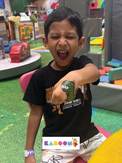 Roar! A young guest shows off his fierce dinosaur temporary tattoo. This is one of our most popular party activities, letting kids express themselves with safe, fun body art.