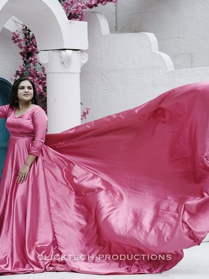 A solo portrait of the bride-to-be, her pink trail gown creating a beautiful, flowing arc against a white architectural set.
