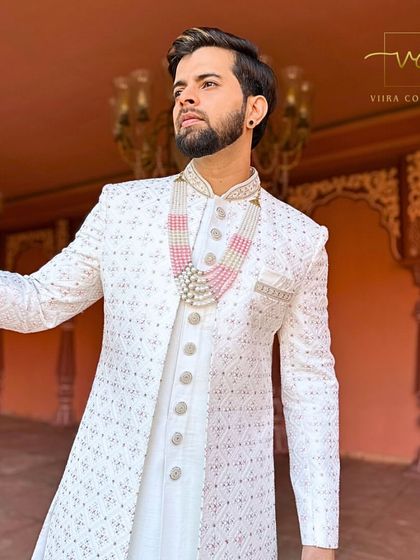 A close-up on the detailed embroidery and pearl necklace of this white sherwani.