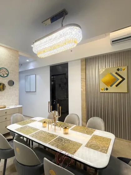 This dining area is designed for memorable gatherings. It features a marble-top table with gold-inlaid placemats, plush velvet chairs, and a stunning crystal chandelier that serves as a focal point.