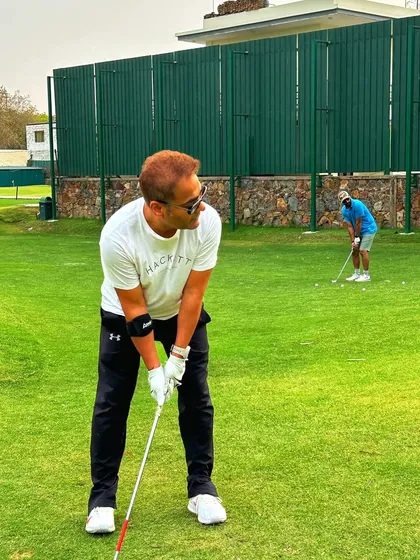 A golfer focuses on his chipping technique, practicing just off the edge of the green.