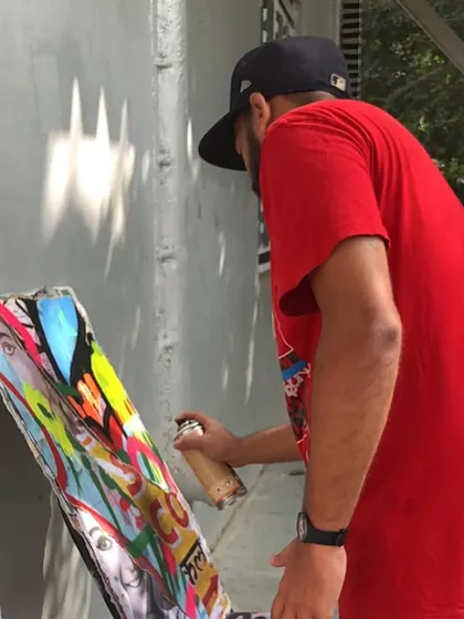 A close-up action shot of me adding the final spray paint details to a décollage canvas. Every layer, from the pasted paper to the final tag, is part of the story.