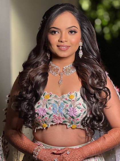 A smiling portrait of the bride, showcasing her beautiful floral lehenga and the fresh, dewy makeup that complements her outfit perfectly.