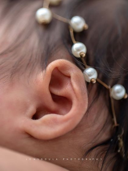 The perfect little swirl of a newborn's ear, adorned with a delicate pearl headband. It’s these tiny features that make them so unique.