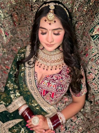 A bride surrounded by the flare of her dark green and maroon embroidered lehenga. A truly royal and dramatic shot.