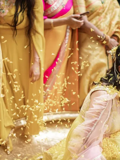 The bride laughing as she is showered with flower petals by her family.