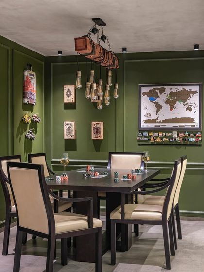 A closer view of the poker table in the entertainment room. The vibrant green paneled walls, unique lighting, and curated wall art create a luxurious and playful atmosphere for social gatherings.